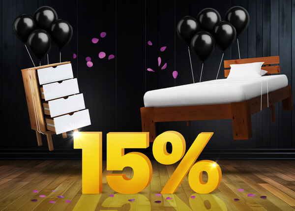 C&oacute;moda y marco de cama de madera con globos negros frente a un letrero amarillo brillante del 15% sobre un suelo de madera oscura.