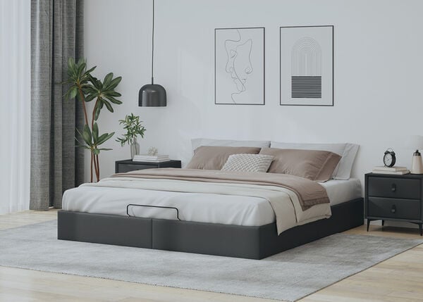 Cama otomana tapizada en gris oscuro con ropa de cama beige y mesitas de noche oscuras en un dormitorio decorado con estilo. 