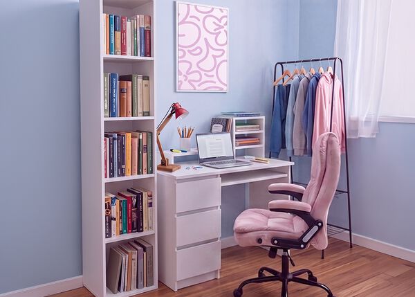 Zona de estudio moderna para estudiantes con escritorio blanco, silla de oficina ergon&oacute;mica, port&aacute;til, librer&iacute;a, mueble de almacenaje y perchero en un dormitorio luminoso y ordenado, pensado para estudiar con comodidad y para el d&iacute;a a d&iacute;a de un estudiante.