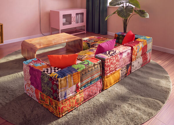 Sof&aacute; modular de patchwork colorido colocado alrededor de una mesa de centro de madera sobre una alfombra redonda en un sal&oacute;n contempor&aacute;neo.