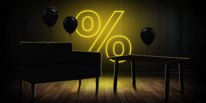 Sofá negro y mesa de madera con globos negros frente a un letrero de porcentaje amarillo brillante sobre un suelo de madera oscura.