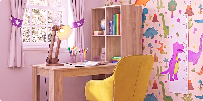 Habitación de estudio infantil luminosa con escritorio de madera, silla amarilla ergonómica, lámpara de escritorio, estantería de almacenaje y papel pintado de dinosaurios, ideal para crear en casa un espacio de aprendizaje organizado y cómodo.