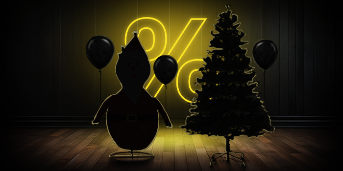 Figura inflable de Papá Noel y árbol de Navidad con globos negros frente a un letrero de porcentaje amarillo brillante sobre un suelo de madera oscura.