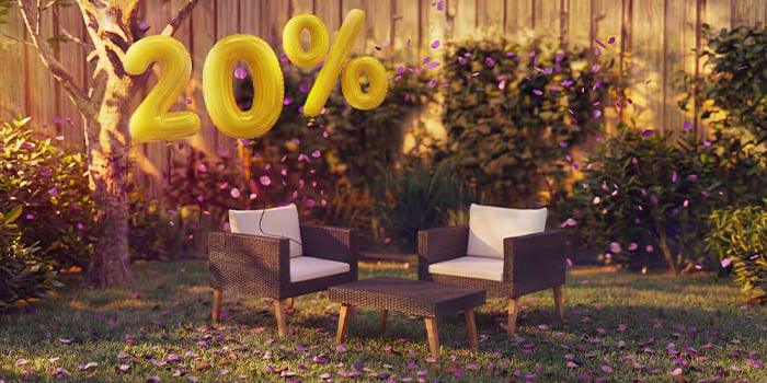 Sillones lounge de ratán para exterior con cojines y una pequeña mesa en un entorno de jardín, decorados con confeti rosa y globos dorados con «20 % de descuento», que destacan ofertas de temporada en muebles lounge de jardín.